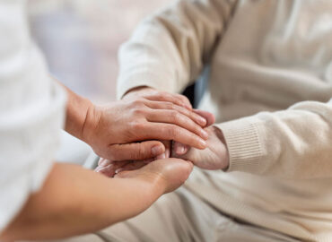 Nurse holing hands with senior patient