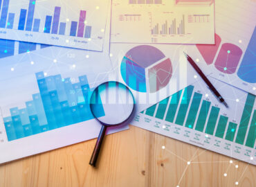 Magnifying glass and documents with analytics data lying on table,selective focus