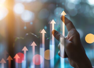 Hand pointing at upward arrow graph, symbolizing growth, success, and positive trends in business or finance.